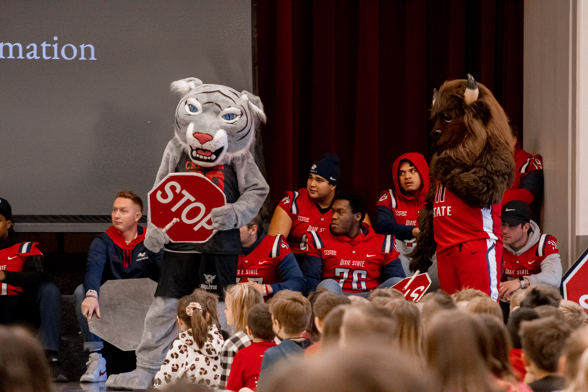 School mascot with Dixie State mascot talking to student in the gym. 